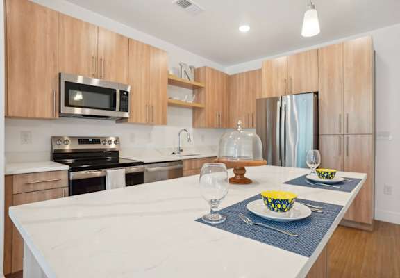 A modern kitchen with a white countertop and wooden cabinets.