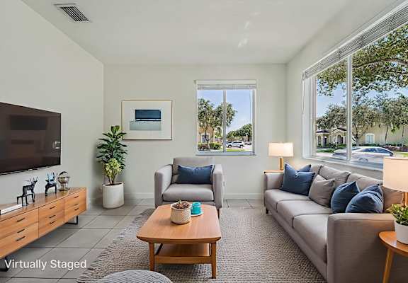 A living room with a couch, a coffee table, a television, and a window.
