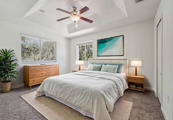 A bedroom with a bed, nightstand, and a ceiling fan.