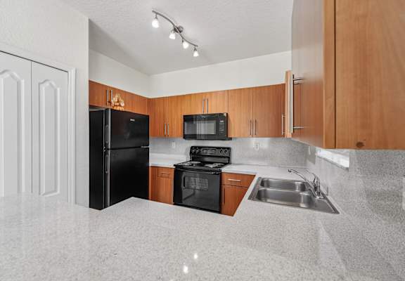 A kitchen with a black refrigerator, black stove, and black microwave.