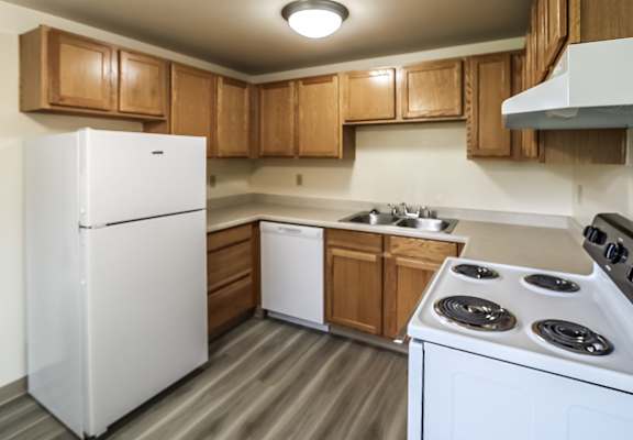 A white refrigerator is in a kitchen with wooden cabinets.