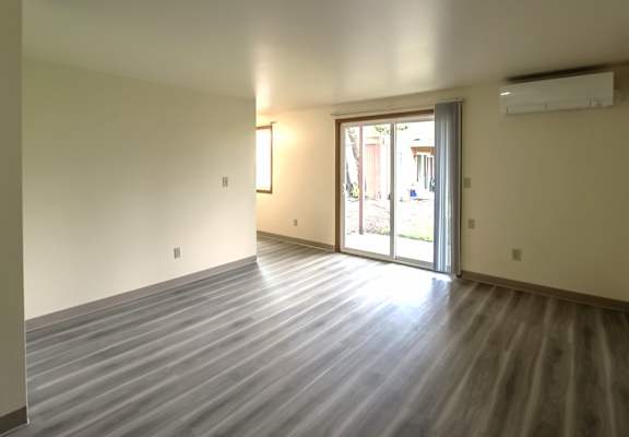 A room with a wooden floor and sliding glass doors.