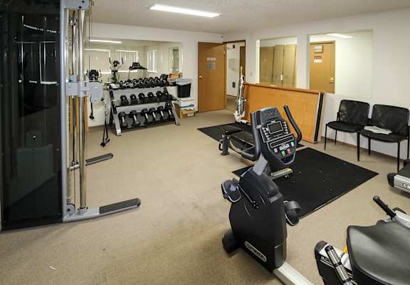 A gym with a variety of equipment including treadmills, weights, and exercise machines.