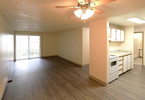 A room with a ceiling fan and wooden flooring.