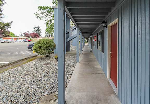 A long grey building with a red door.