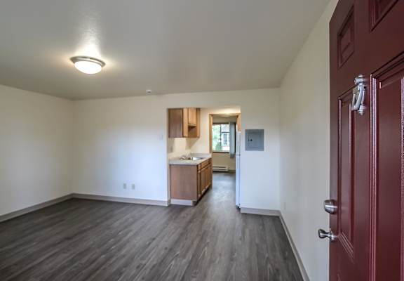 A room with a red door and a kitchen area in the background.