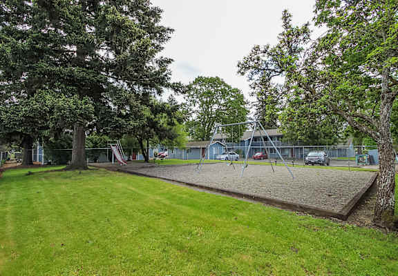 A playground with a swing set and a slide in the background.