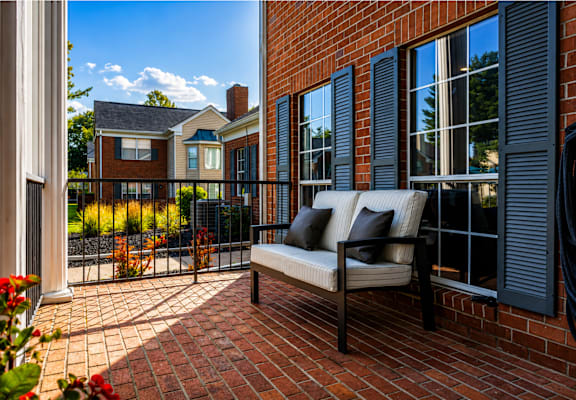 A patio with a couch and a view of a house.