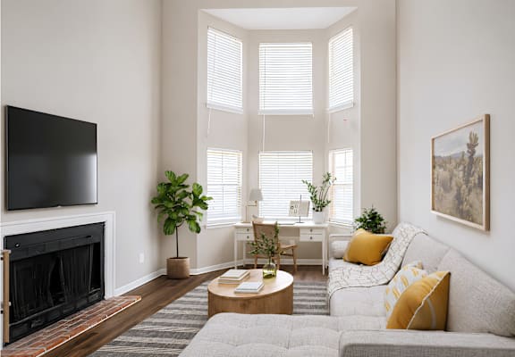 A living room with a grey couch, a fireplace, and a painting on the wall.