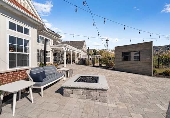A patio with a bench, table, and a small building.