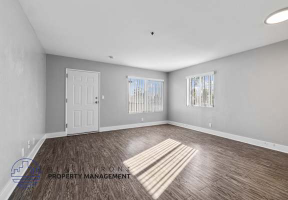 A spacious room with wooden flooring and a white door.