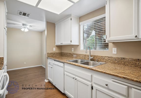 A kitchen with white cabinets and a granite countertop.