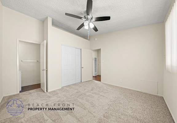 A spacious room with a ceiling fan and carpeted floor.