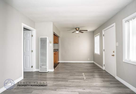 A spacious room with a ceiling fan and wooden flooring.