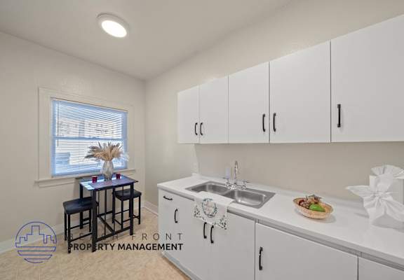 A kitchen with white cabinets and a sink.
