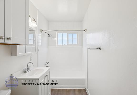A white bathroom with a sink, mirror, and bathtub.