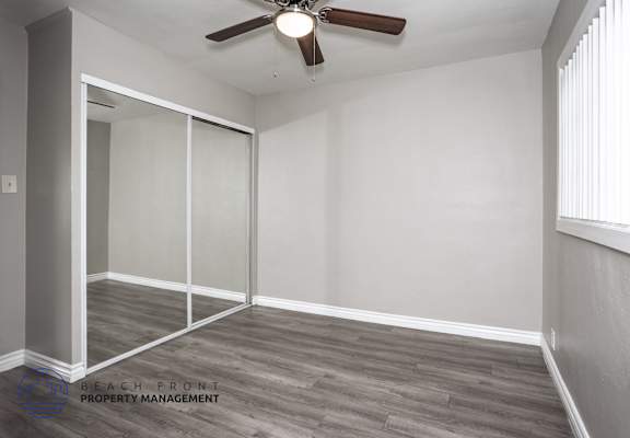 A room with a ceiling fan and sliding glass doors.