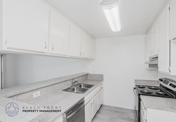 A kitchen with white cabinets and a granite countertop.