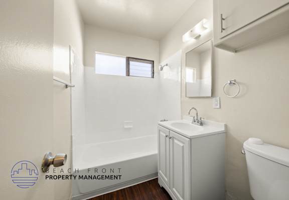 A white bathroom with a sink, mirror, and bathtub.