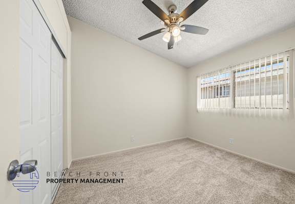 A room with a ceiling fan and a window with blinds.