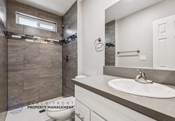 A bathroom with a sink, mirror, and tiled shower.