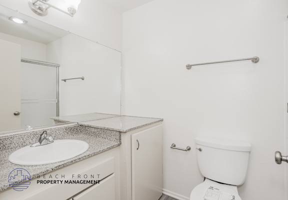 A white toilet sits next to a white sink in a small bathroom.