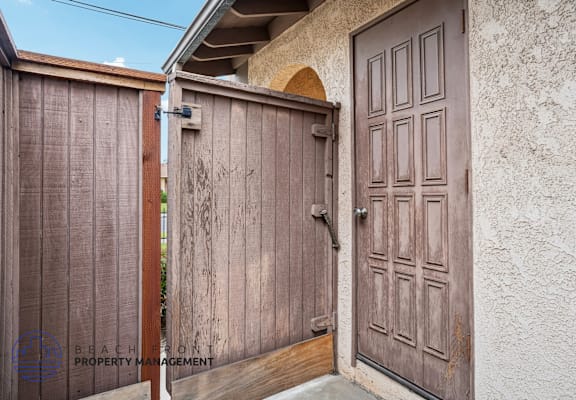 A wooden gate is closed with a brown door to the right.