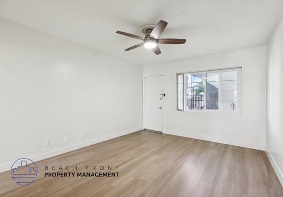 A room with a ceiling fan and wooden flooring.