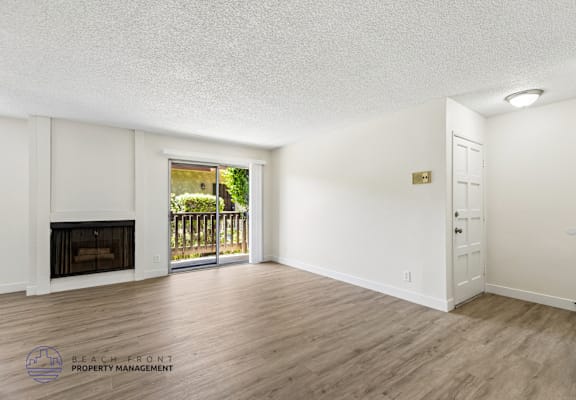 A spacious room with a fireplace and sliding glass doors leading to a balcony.