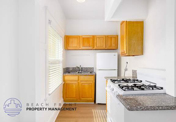 A kitchen with a stove, sink, and cabinets.