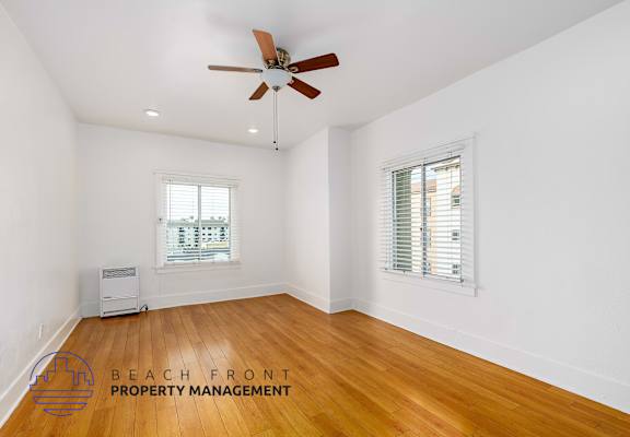 A room with a ceiling fan and wooden flooring.