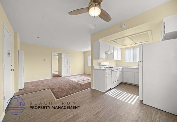 A kitchen area with a refrigerator, sink, and cabinets.