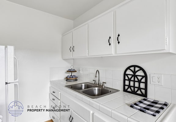 A kitchen with white cabinets and a checkered towel on the counter.