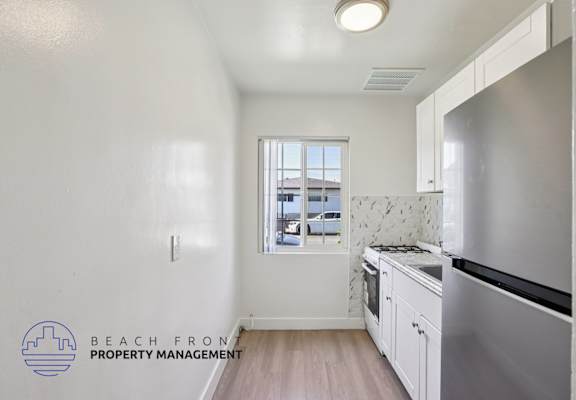 A kitchen with a stainless steel refrigerator and wooden floors.