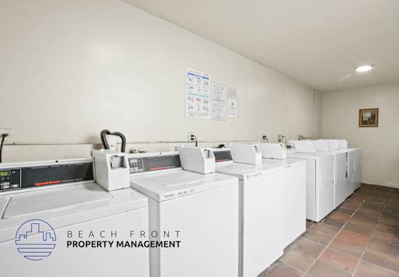 A laundry room with washers and dryers and a sign that says Beach Front Property Management.