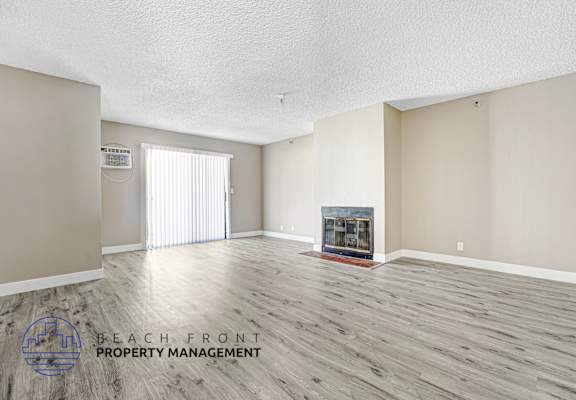 A spacious room with a fireplace and a logo for Beach Front Property Management.