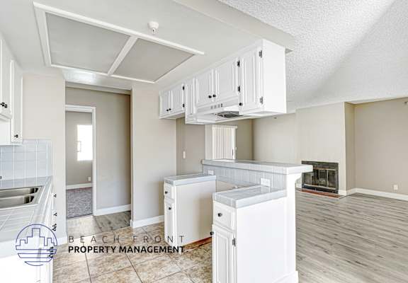 A kitchen with white cabinets and a refrigerator.