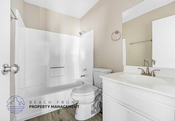 A white bathroom with a toilet, sink, and shower.
