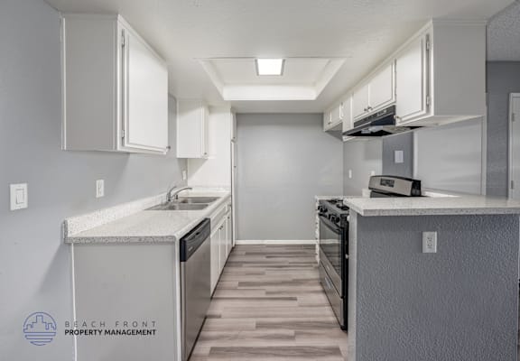 A kitchen with a stove, sink, and cabinets.
