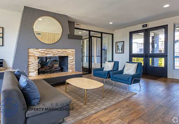 A modern living room with a fireplace and blue chairs.