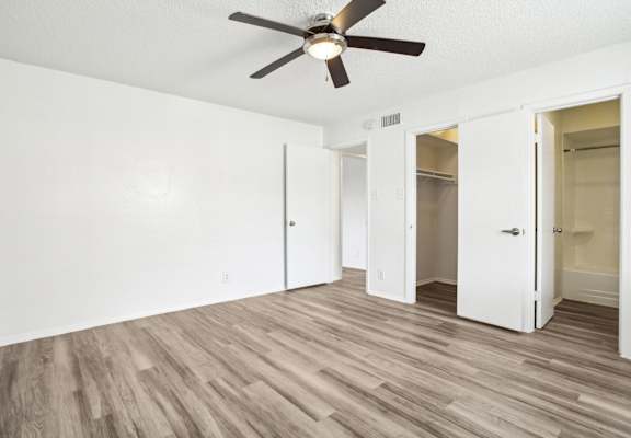 A room with a ceiling fan and wooden flooring.