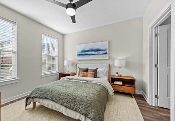 A bedroom with a bed, nightstand, and a painting on the wall.