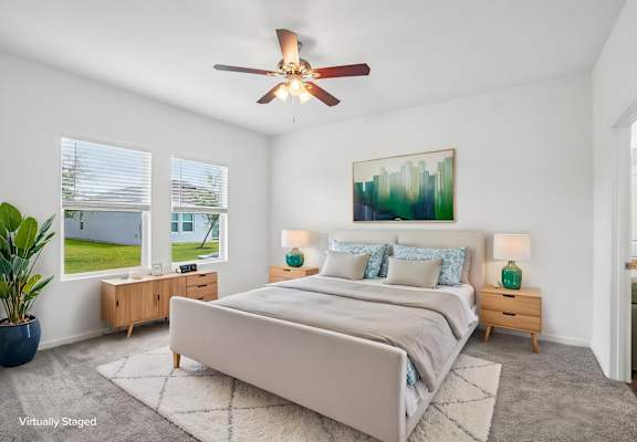 A bedroom with a large bed, a ceiling fan, and a painting on the wall.
