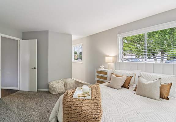Bright bedroom with plush bedding and natural light at Ashford at Geneva – pet-friendly apartments in Geneva, Illinois