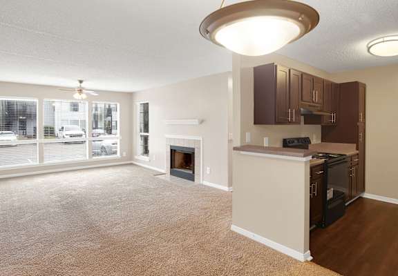 A living room with a fireplace and a kitchen area with a refrigerator and microwave.