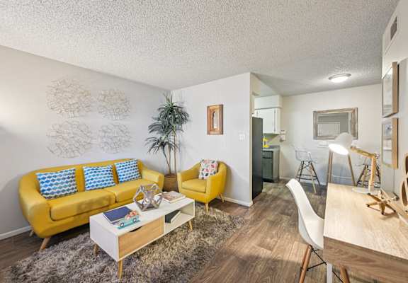 A living room with a yellow sofa and a white coffee table.