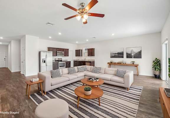 A living room with a white couch, a coffee table, and a ceiling fan.