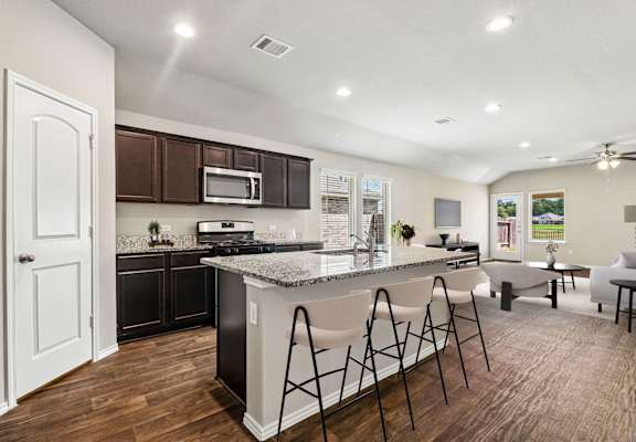 A modern kitchen with dark brown cabinets and a white island.