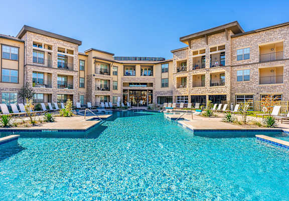 A large swimming pool in front of a multi-story residential building.