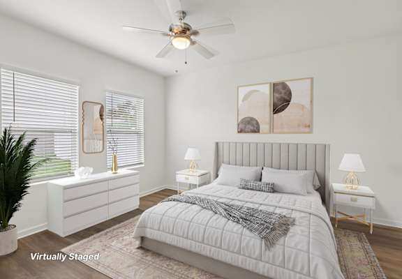 A bedroom with a large bed, a ceiling fan, and a potted plant.